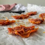 pieces of crispy prosciutto on a parchment lined baking sheet