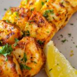 crispy halloumi cheese sliced up on a plate with a lemon wedge and fresh parsley