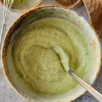 green sauce in a bowl with a spoon next to a little whisk on top of a small bowl