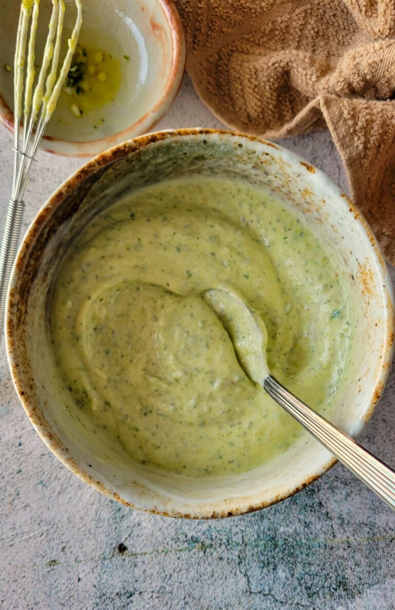 green sauce in a bowl with a spoon next to a little whisk on top of a small bowl