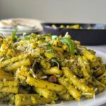 plate of pasta with pesto sauce, fresh parmesan and basil