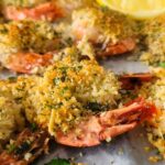 shrimp on a parchment lined baking sheet with lemon and parsley