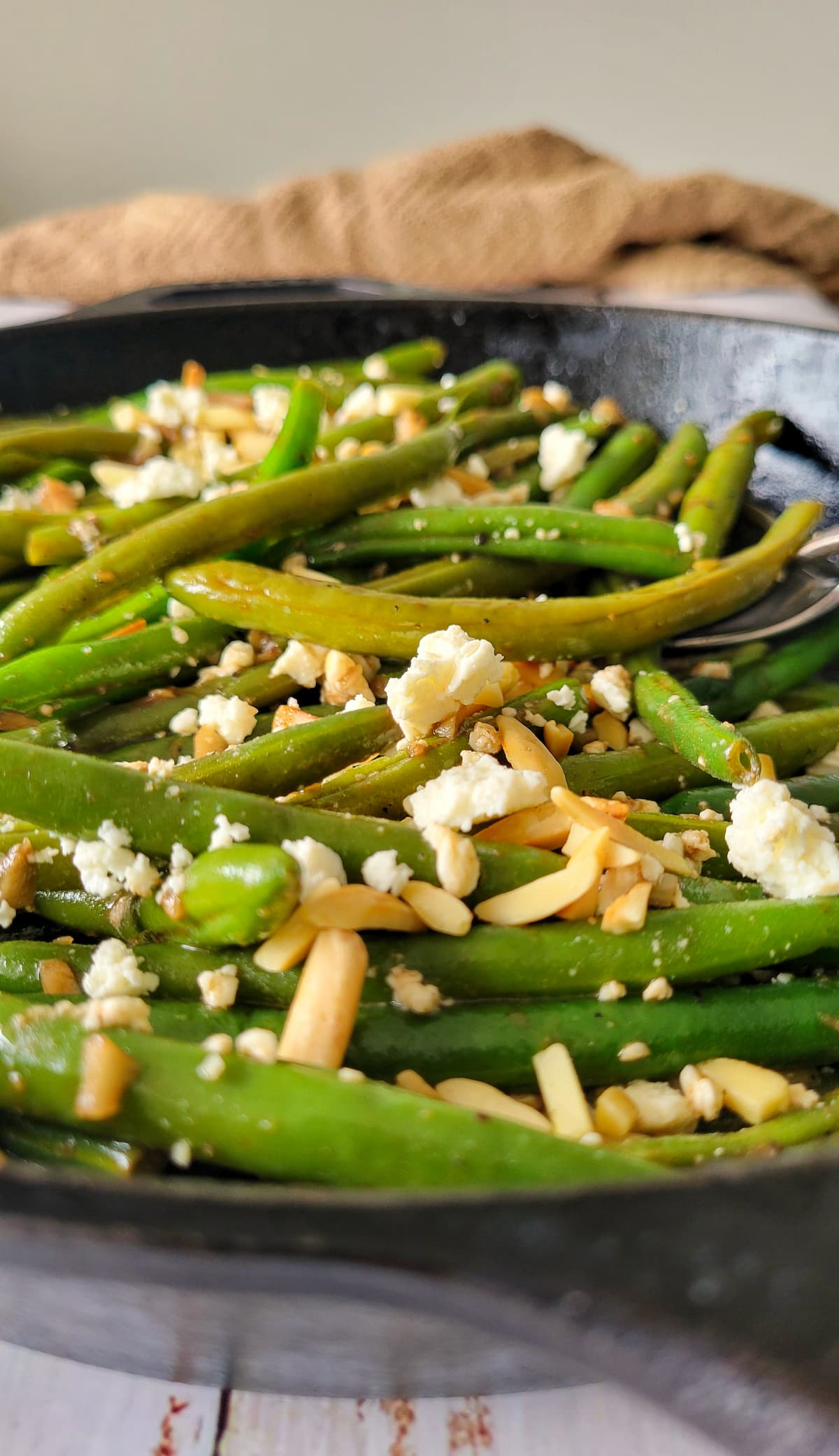 cooked green beans in a skillet with feta and almonds