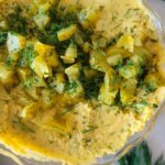 dill pickle hummus in a bowl with chopped dill and pickles
