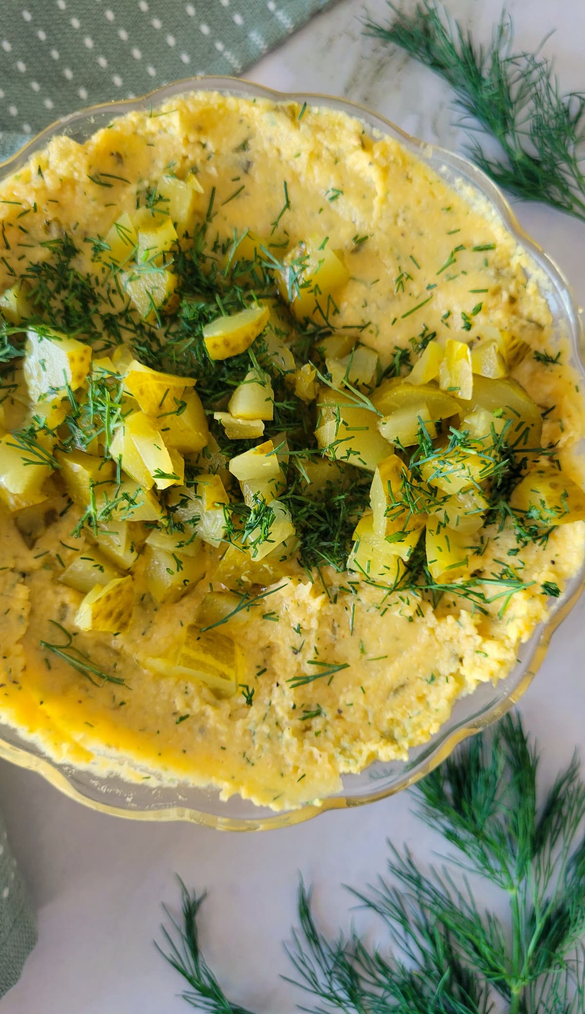 dill pickle hummus in a bowl with chopped dill and pickles