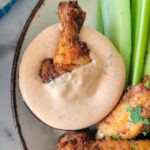wing in an orange sauce on a plate with celery and more wings