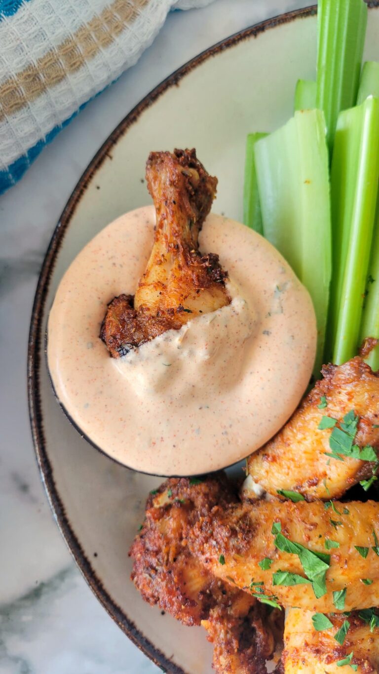 wing in an orange sauce on a plate with celery and more wings