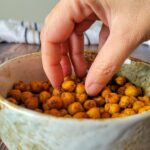 hand taking some crispy chickpeas out of a bowl.