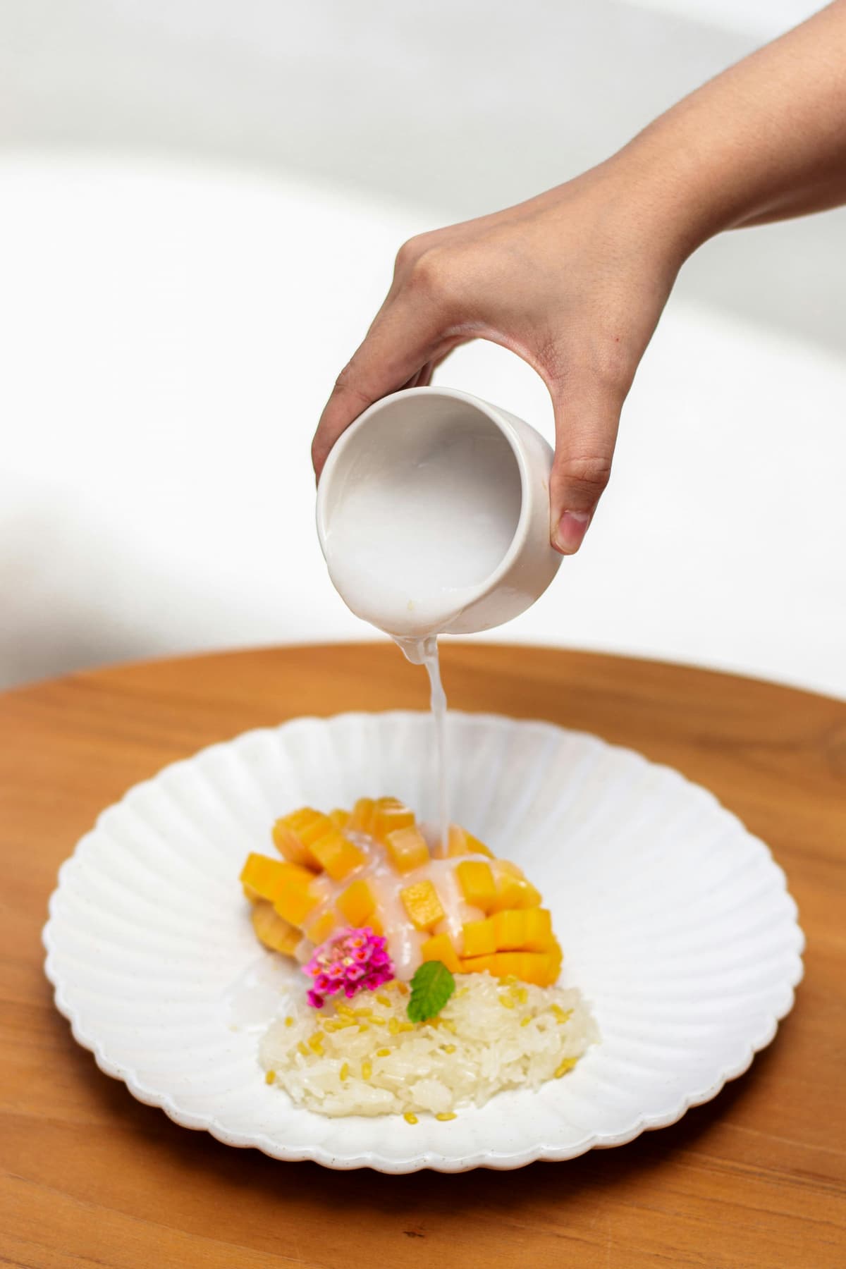 coconut milk pouring over a bowl of mango sticky rice