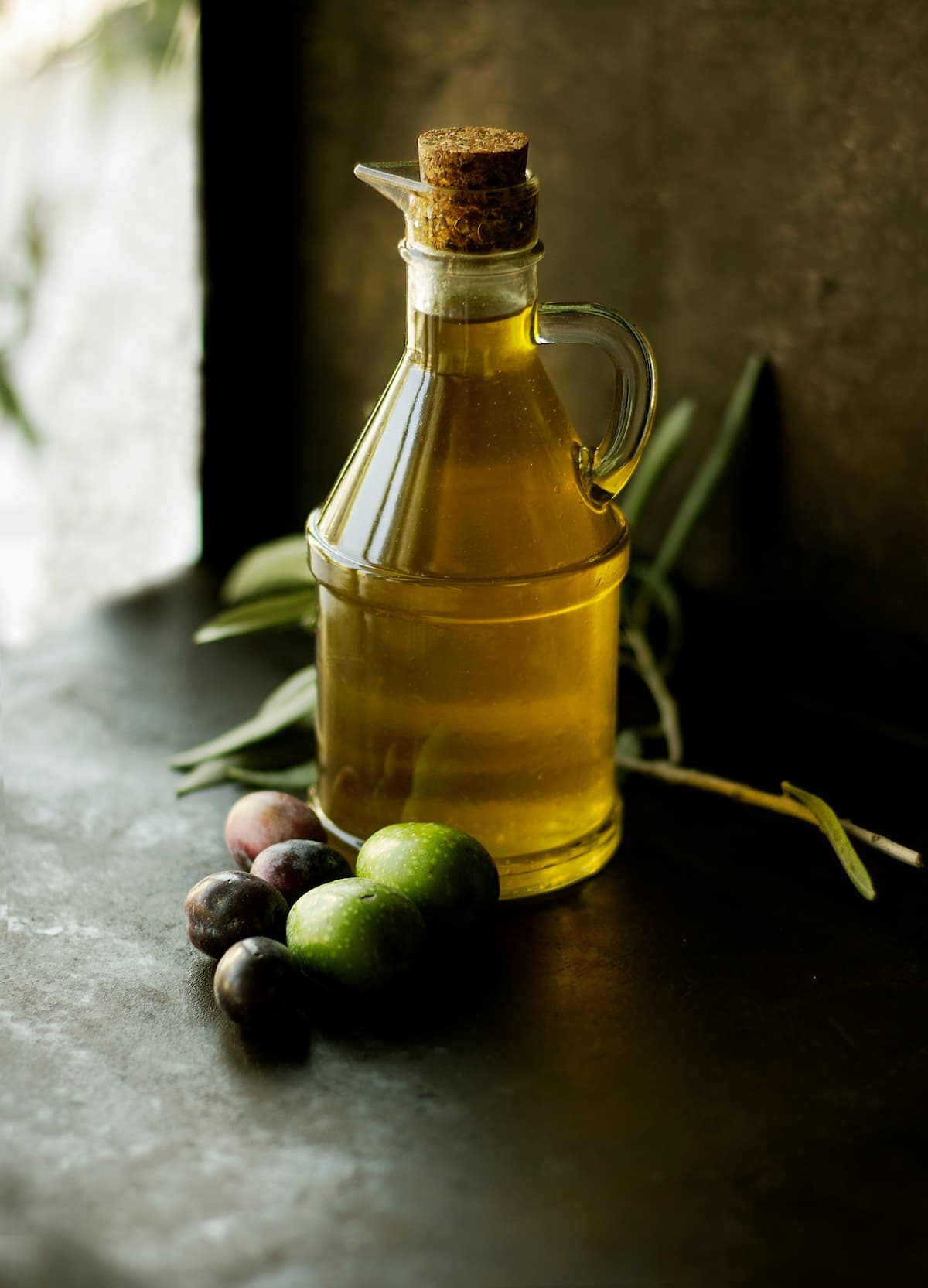 bottle of olive oil next to olives