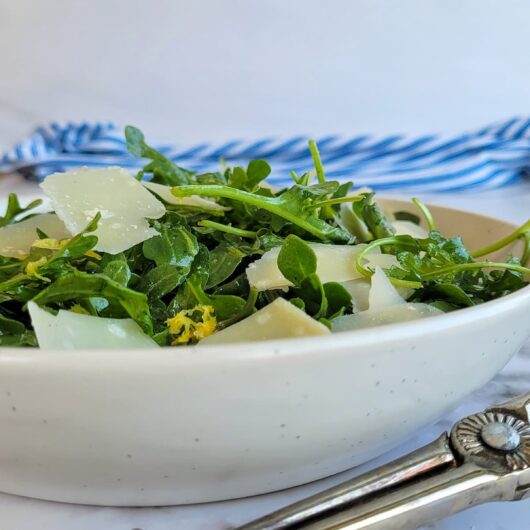 bowl of arugula salad with parmesan petals and lemon zest