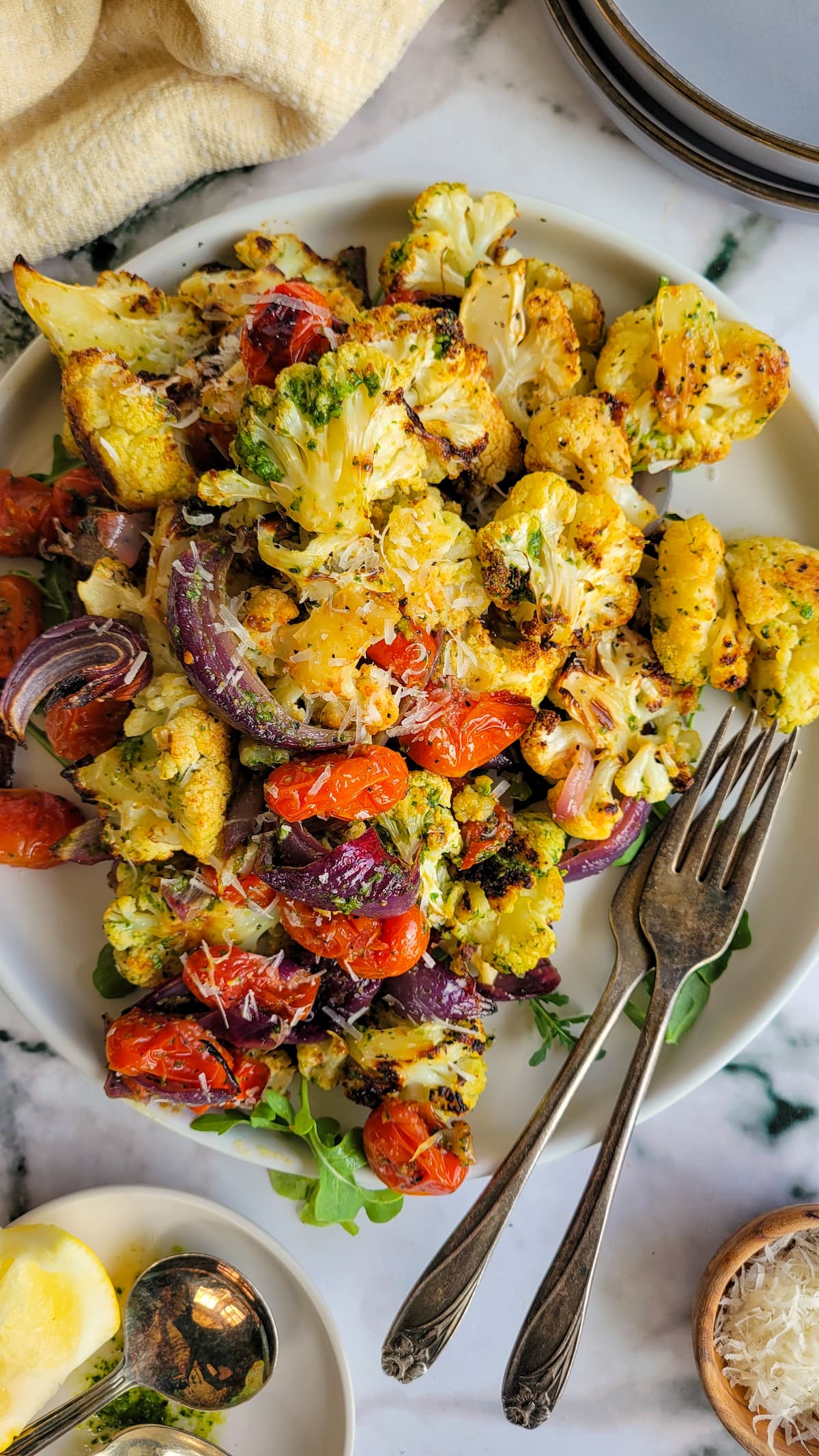 plate of cauliflower with pesto with sliced red onions, cherry tomatoes, and arugula