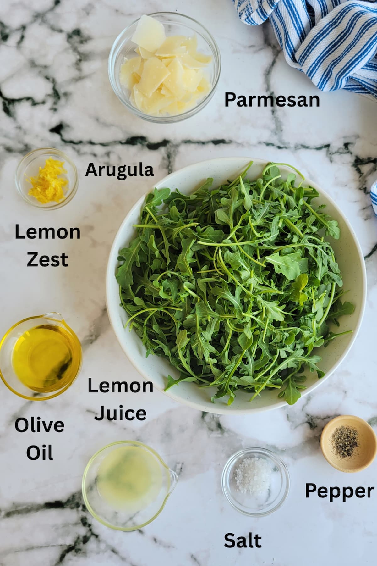 ingredients for simple arugula salad - arugula, lemon juice, lemon zest, parmesan, olive oil, salt, pepper