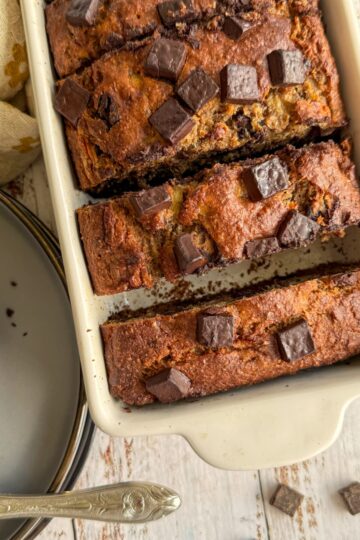 cooked sliced banana bread with chocolate chunks in a loaf pan