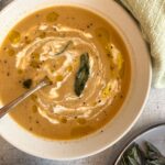bowl of artichoke soup with swirled cream and crispy sage