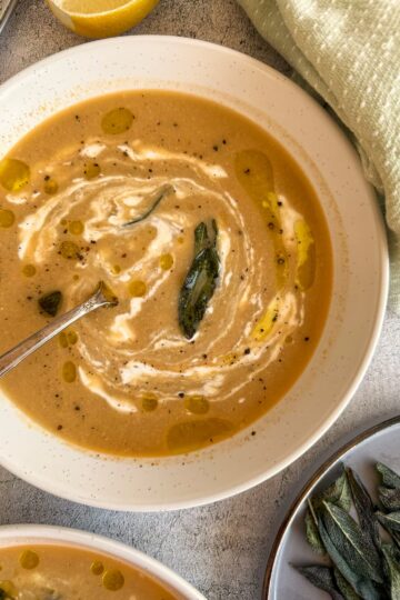 bowl of artichoke soup with swirled cream and crispy sage
