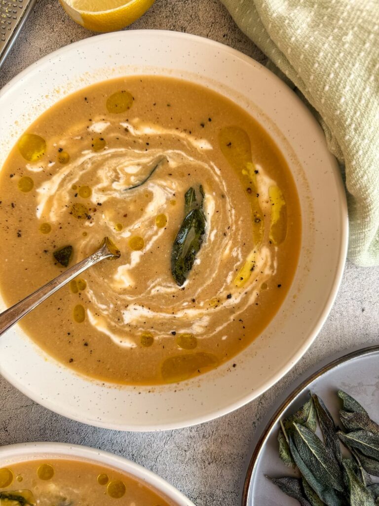 bowl of artichoke soup with swirled cream and crispy sage