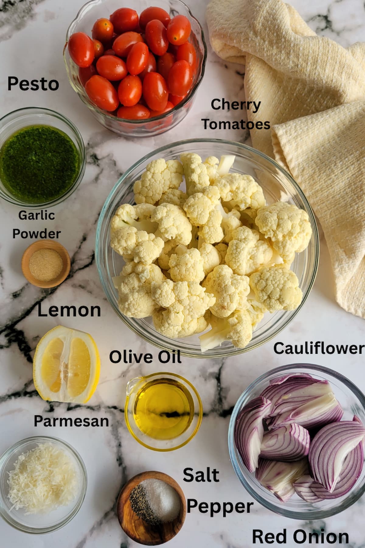 ingredients for pesto cauliflower -cauliflower, pesto, cherry tomatoes, red onions, garlic powder, lemon, olive oil, salt, pepper, parmesan