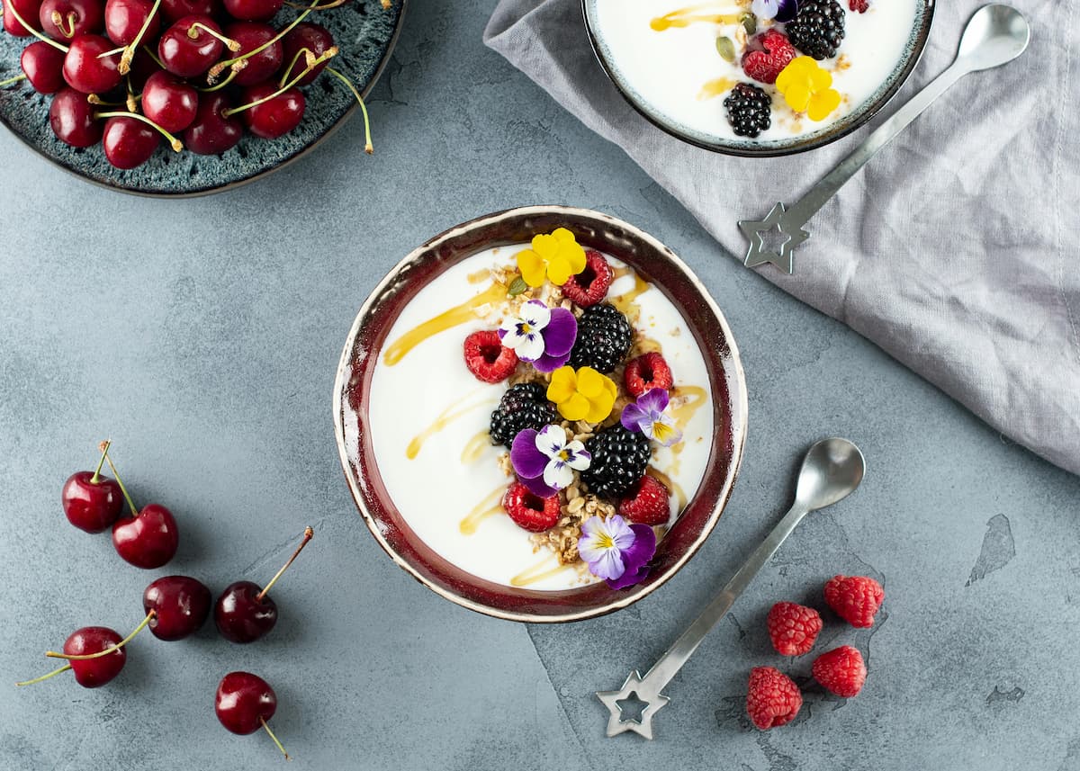 yogurt bowl with berries, flowers, and honey