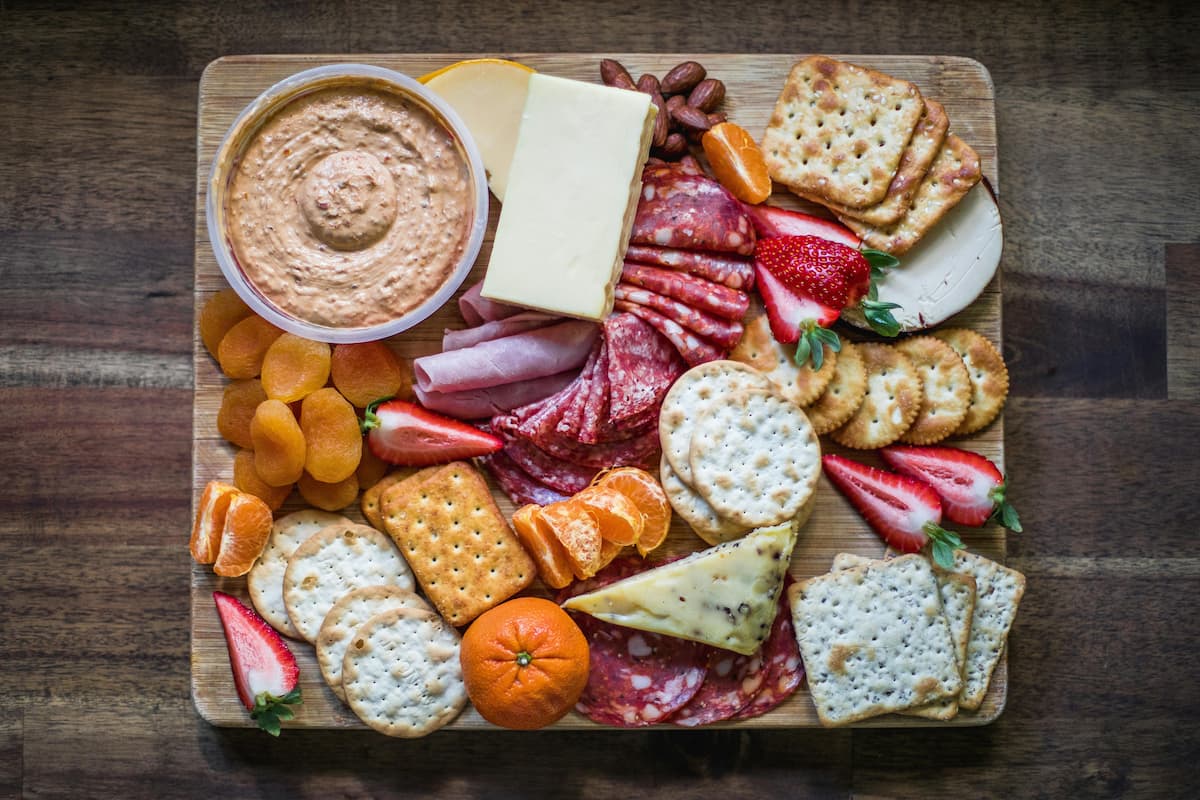 charcuterie board with cheeses, fruits, crackers, and dips
