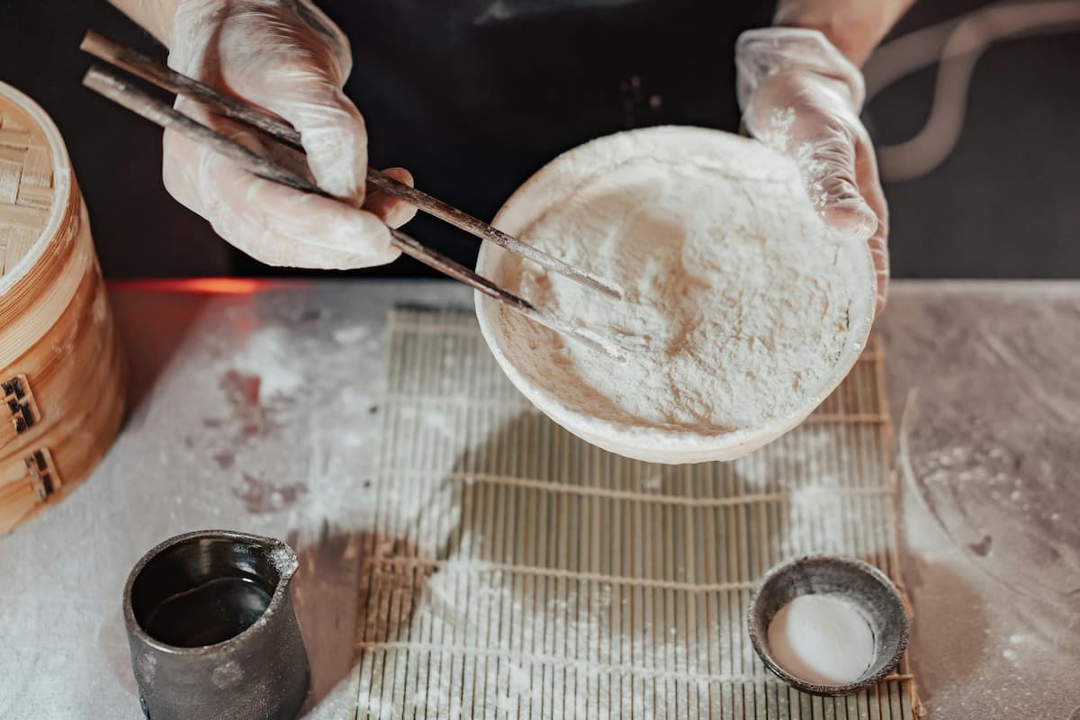 hands holding a bowl of rice flour with chopsticks over it