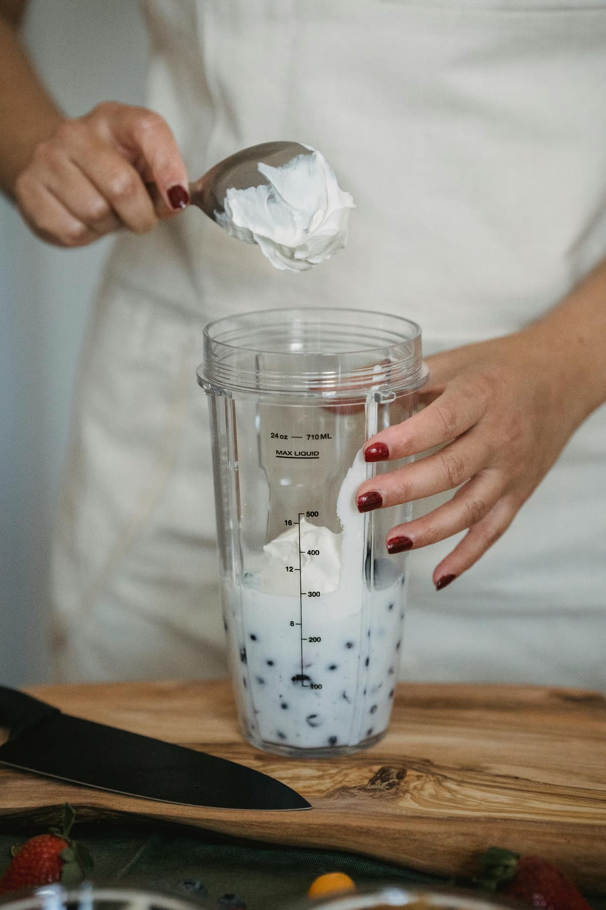 hand adding yogurt to a jar with blueberries and milk