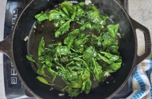 garlic spinach sautéing in a cast iron skillet