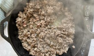 ground beef cooking in a cast iron skillet