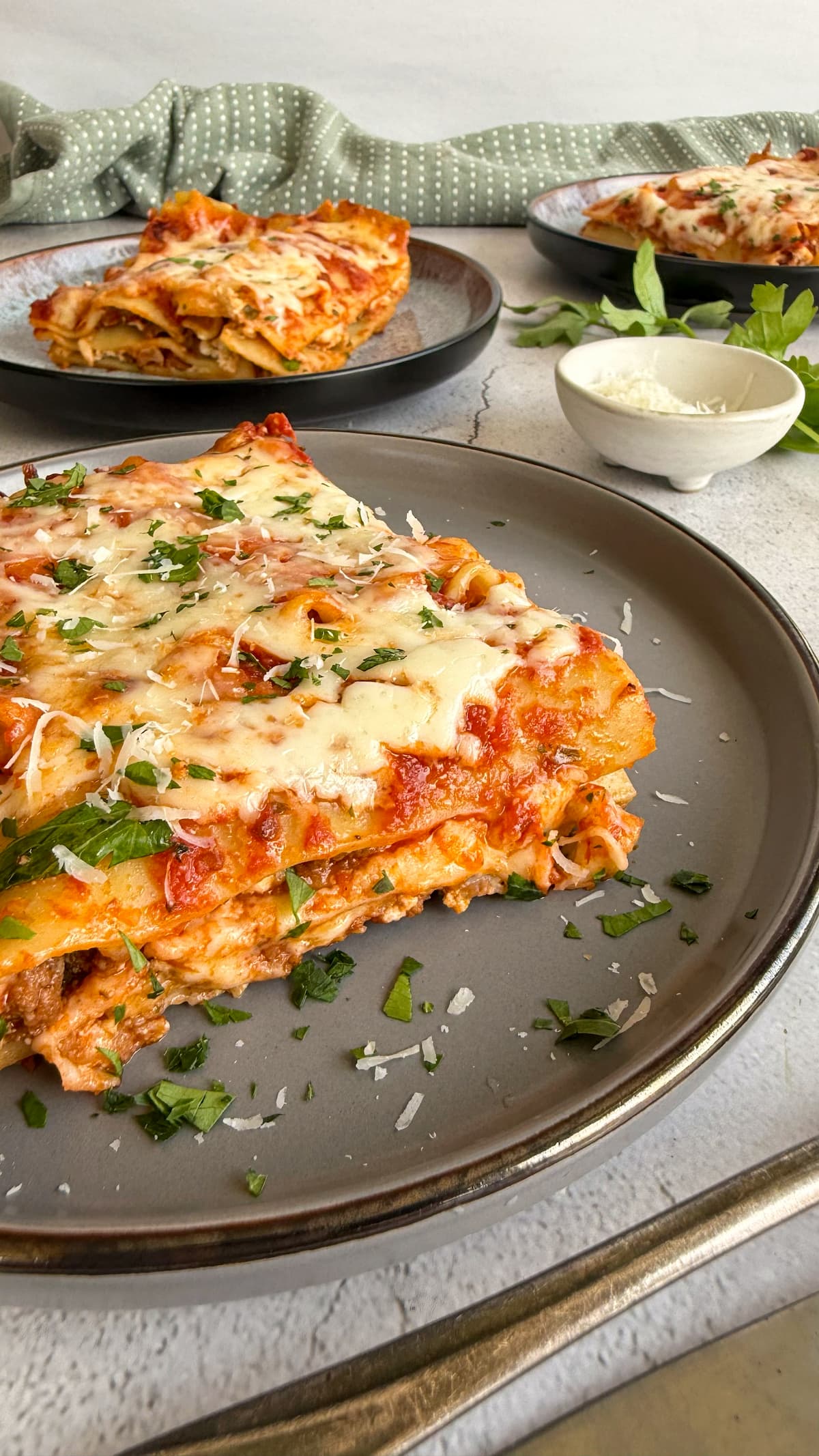 slices of lasagna on plates with fresh parm and parsley