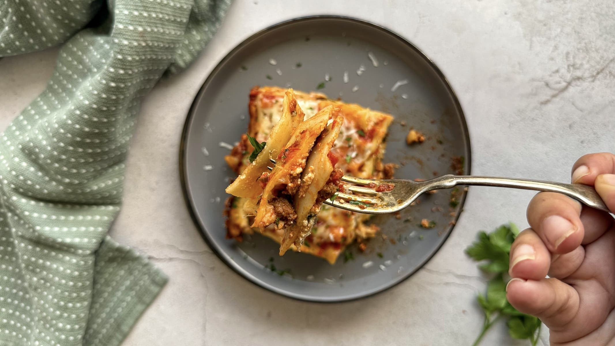 forkful of lasagna over a plate with more