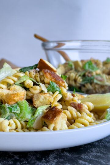 caesar pasta salad on a plate, bowl with more in the background