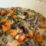 bowl of creamy soup with mushrooms, carrots, celery, onions, wild rice, and parsley