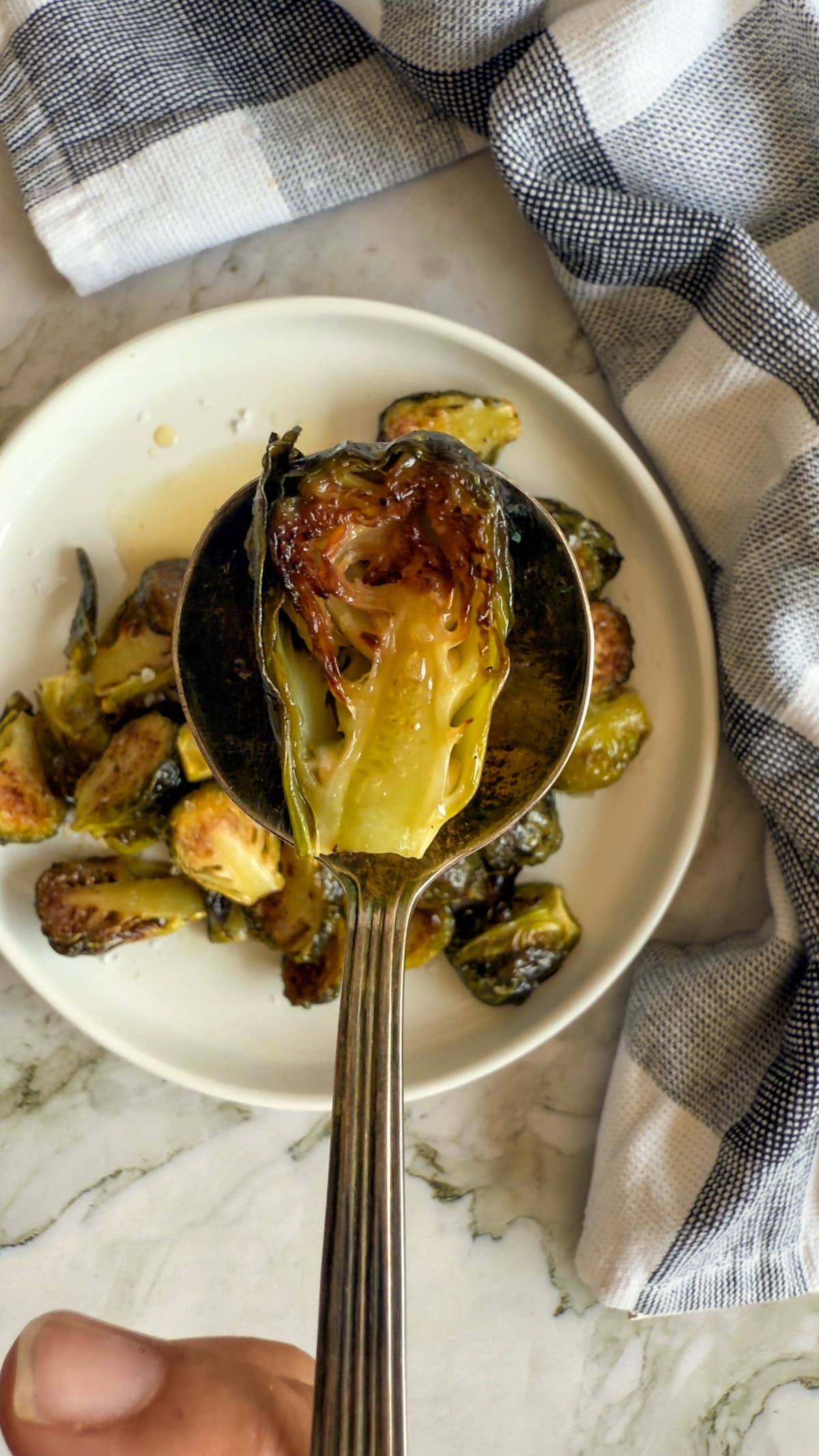 roasted brussel sprout on a spoon over a plate with more
