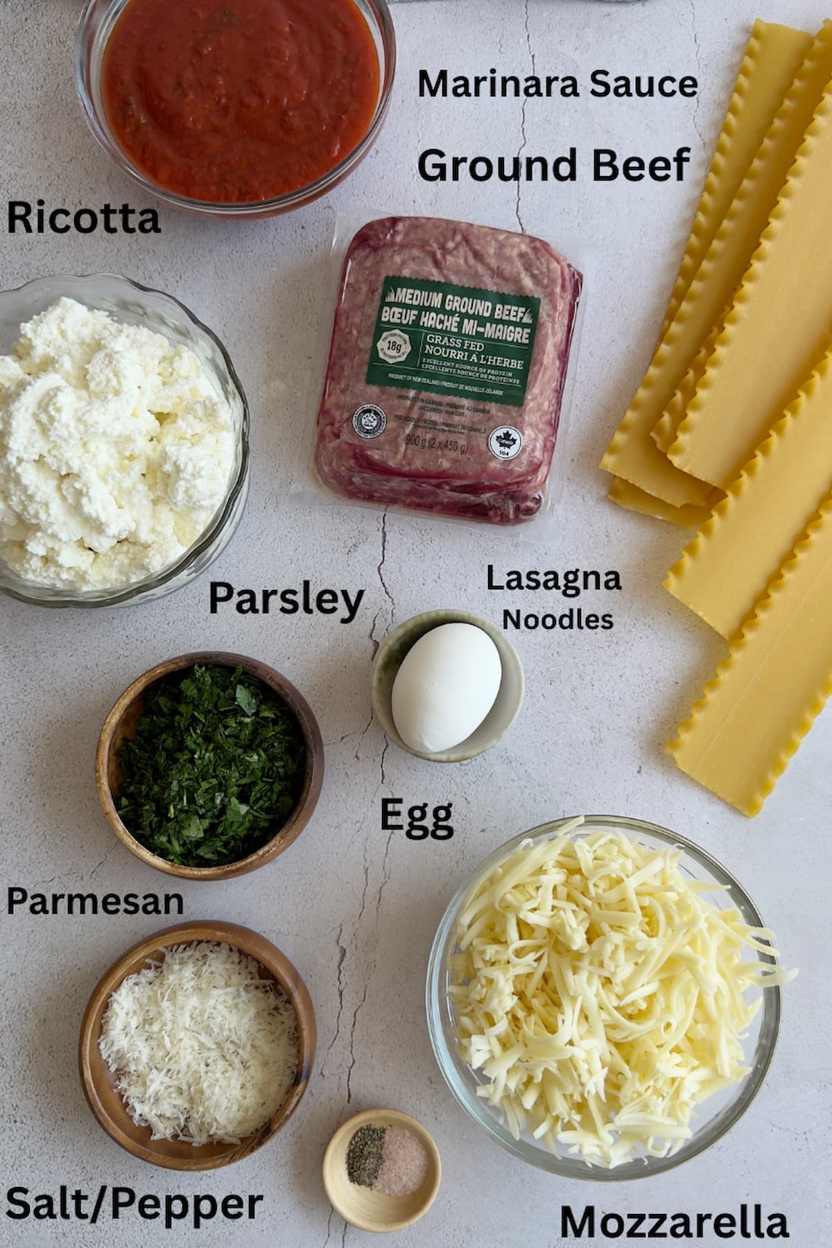 ingredients for easy lasagna recipe with ricotta - lasagna noodles, ground beef, marinara sauce, ricotta, parmesan, mozzarella, parsley, salt, pepper, egg