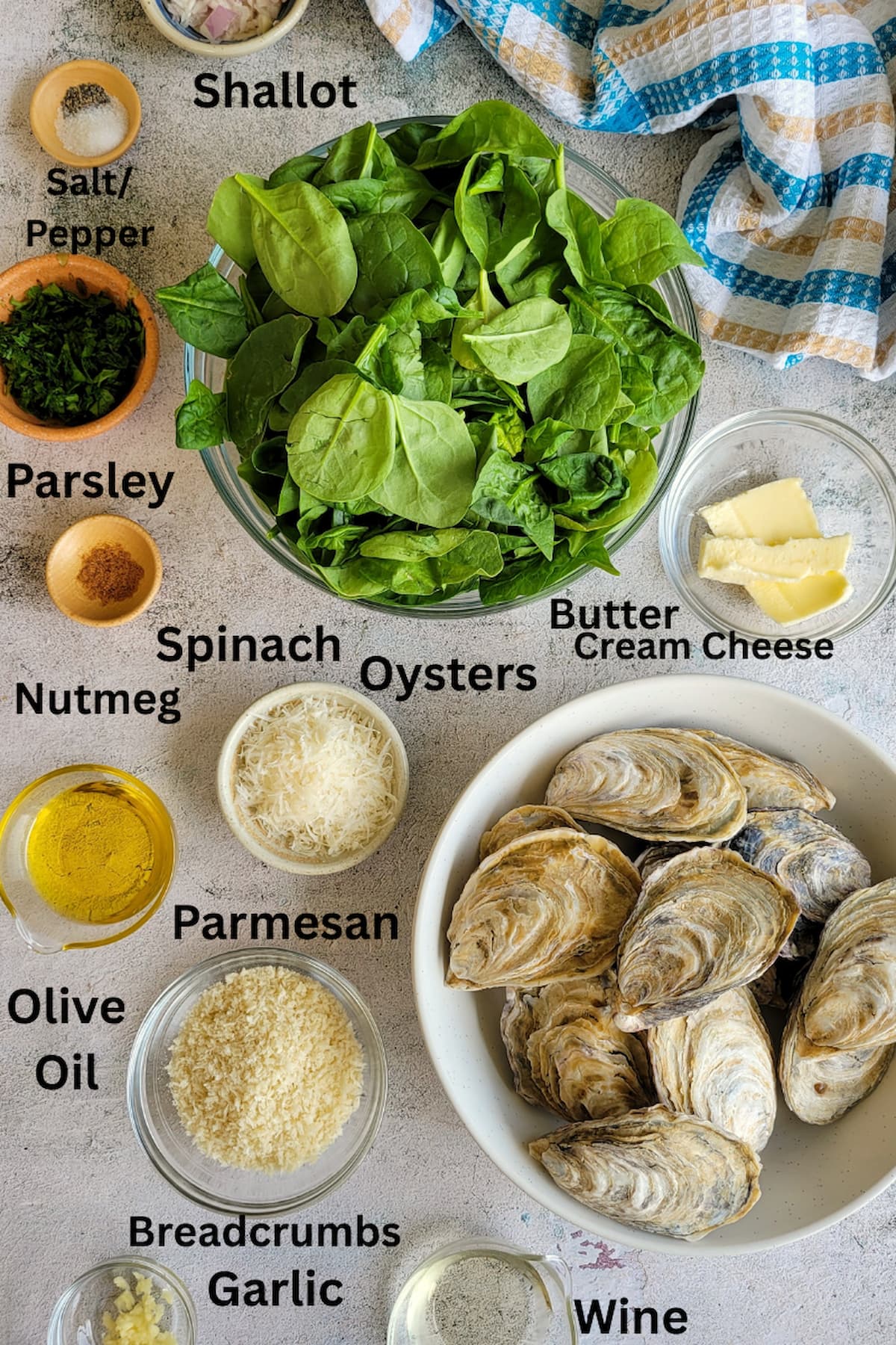 ingredients for baked oysters recipe - shallot, salt, pepper, spinach, parmesan, parsley, oysters, nutmeg, olive oil, breadcrumbs, cream cheese, butter, garlic, wine