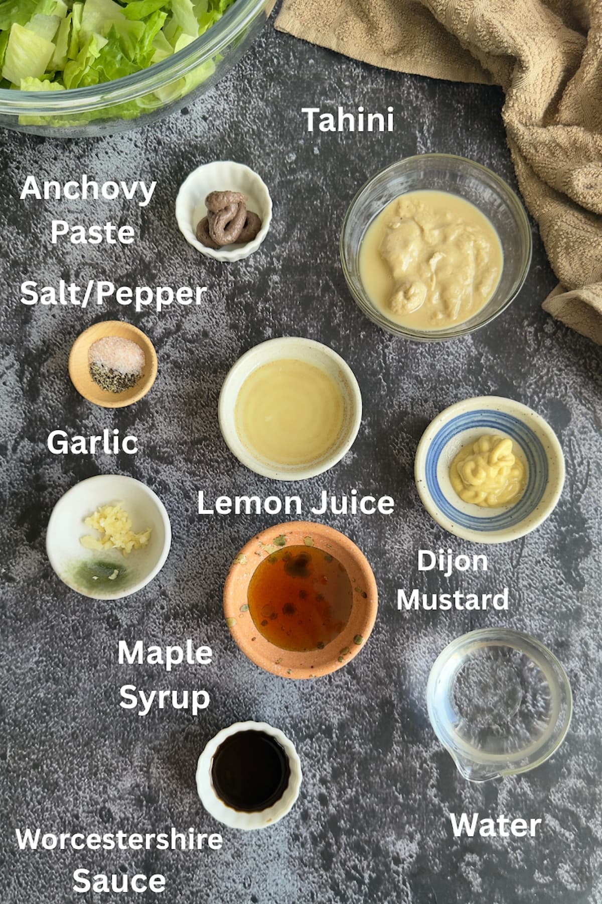 ingredients for tahini caesar dressing - anchovy paste, tahini, salt/pepper, lemon juice, dijon mustard, water, worcestershire sauce, maple syrup, garlic