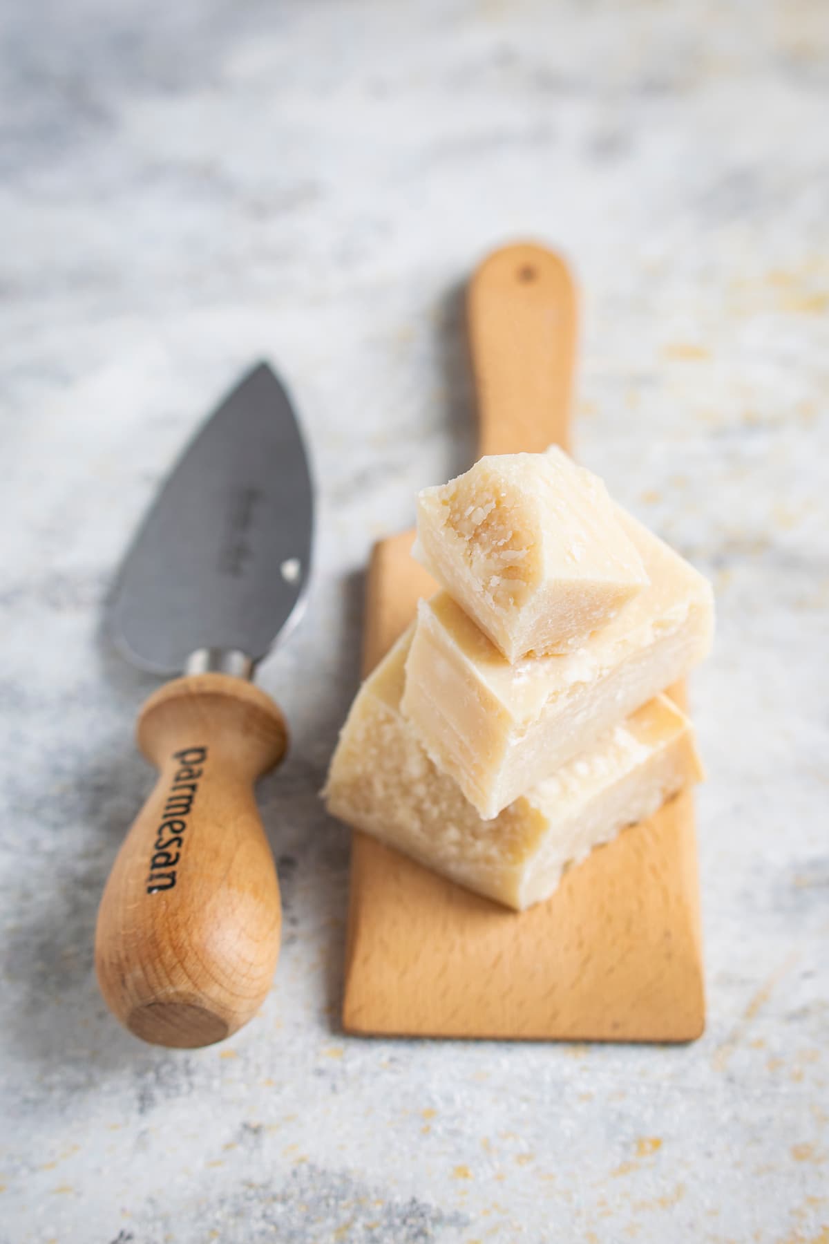 slices of parmesan cheese on a cutting board next to a knife