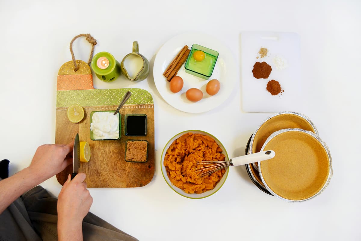 someone baking pumpkin pies, slicing lemon on a cutting board