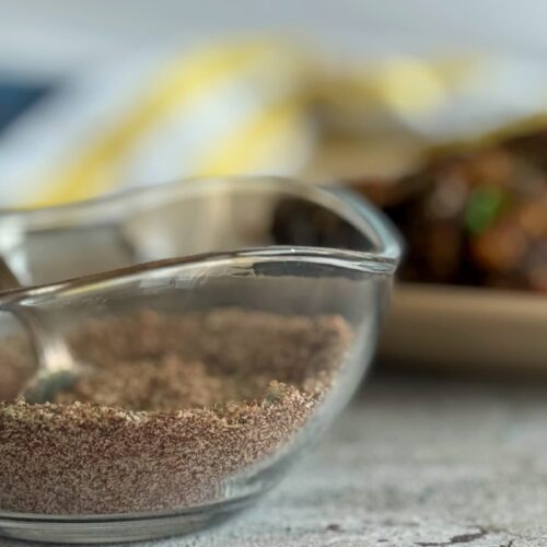 seasoning in a bowl in front of a cooked meatloaf