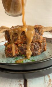 gravy pouring over two slices of meatloaf on a plate
