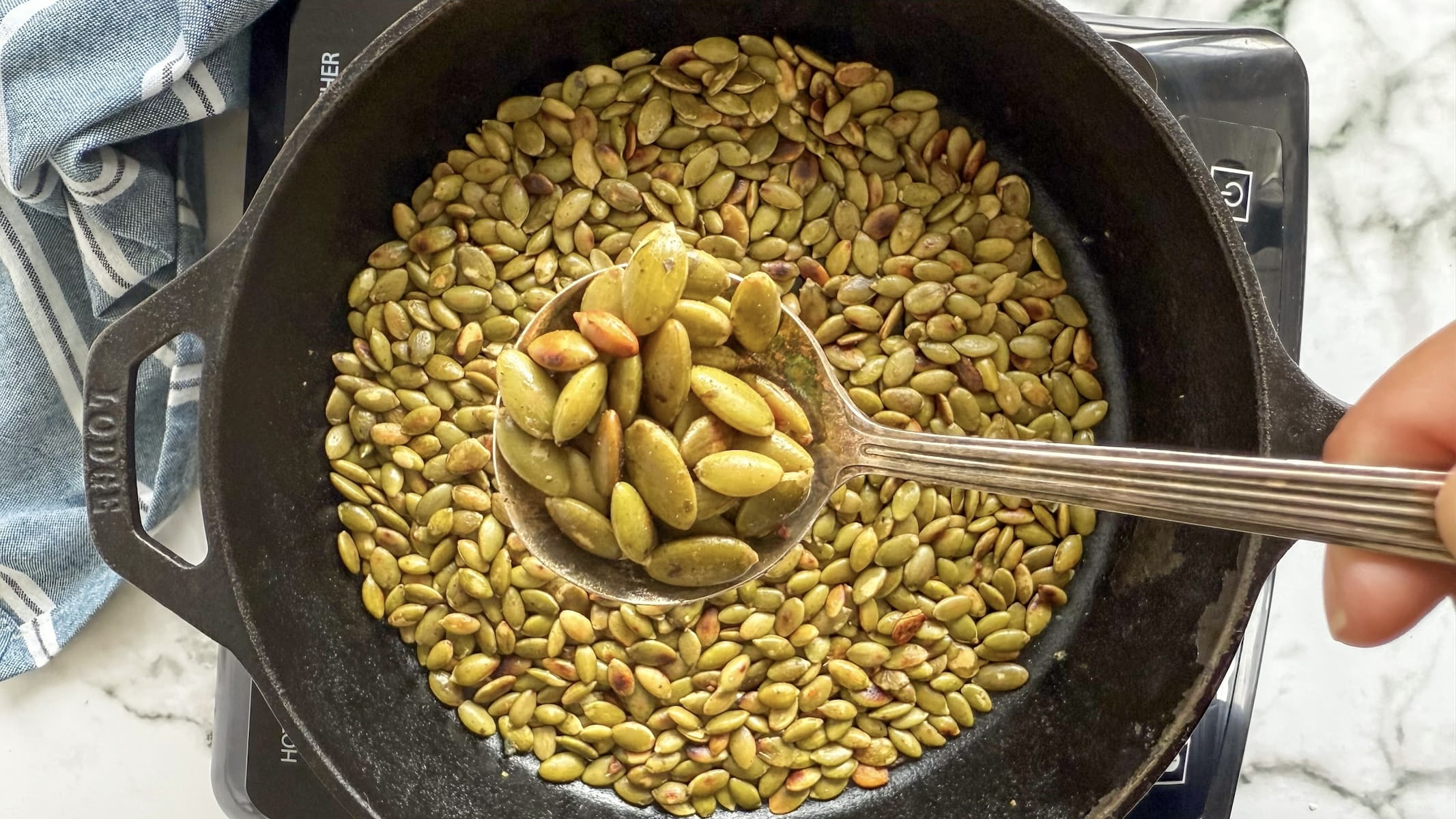 spoonful of toasted pepitas over a cast iron skillet with more