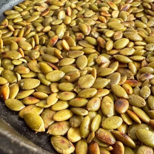 side view of toasted pumpkin seeds in a cast iron skillet