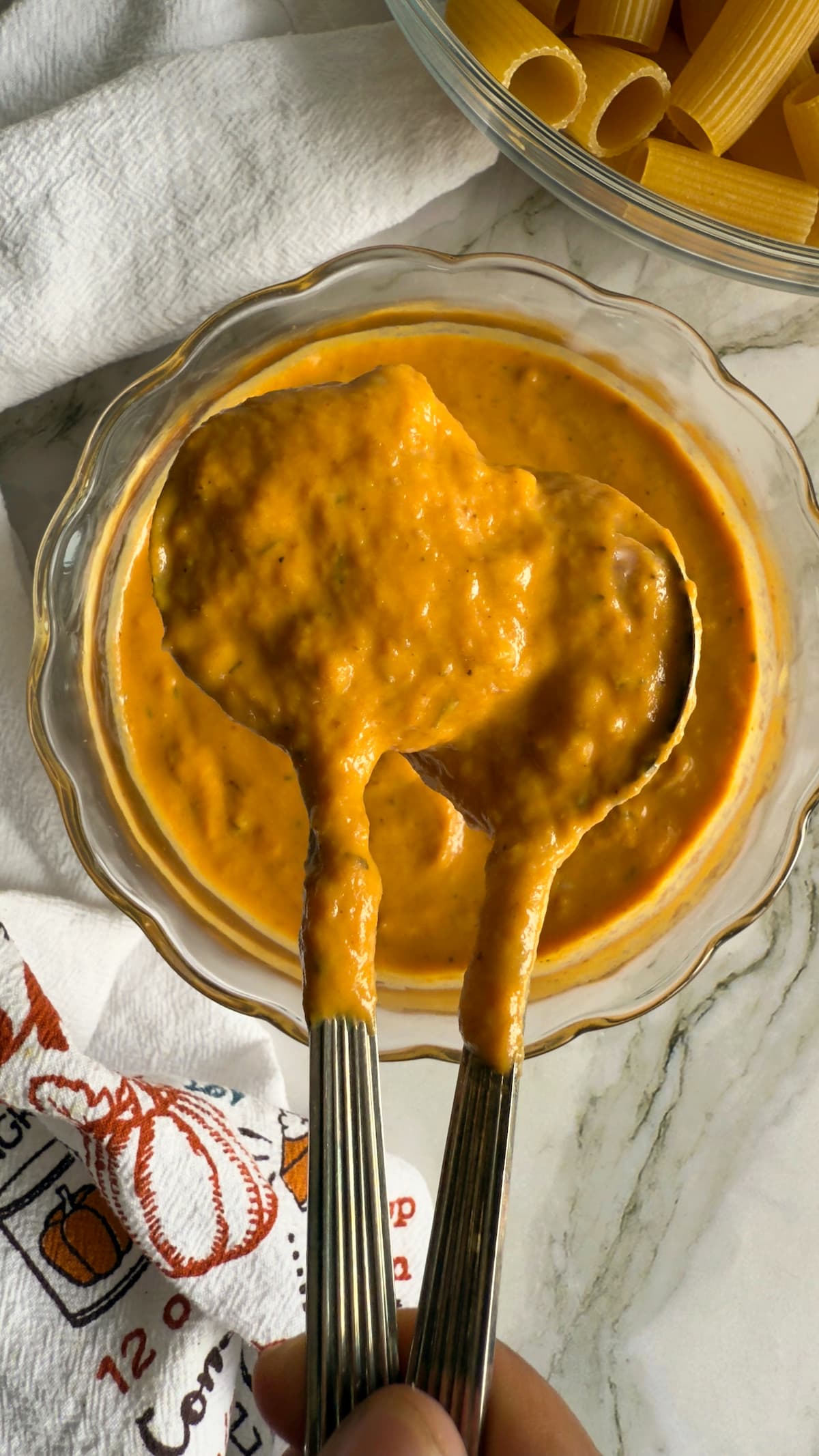 two spoonfuls of orange sauce over a bowl with the rest of it
