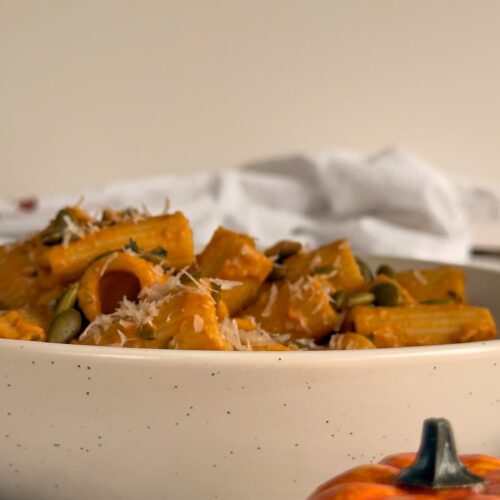 rigatoni in pumpkin sauce with pepitas and parmesan in a bowl