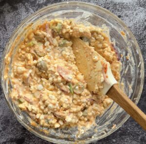 cottage cheese in a bowl mixed with tomato sauce and chopped pizza toppings