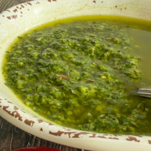 basil chimichurri in a bowl, two red peppers in front