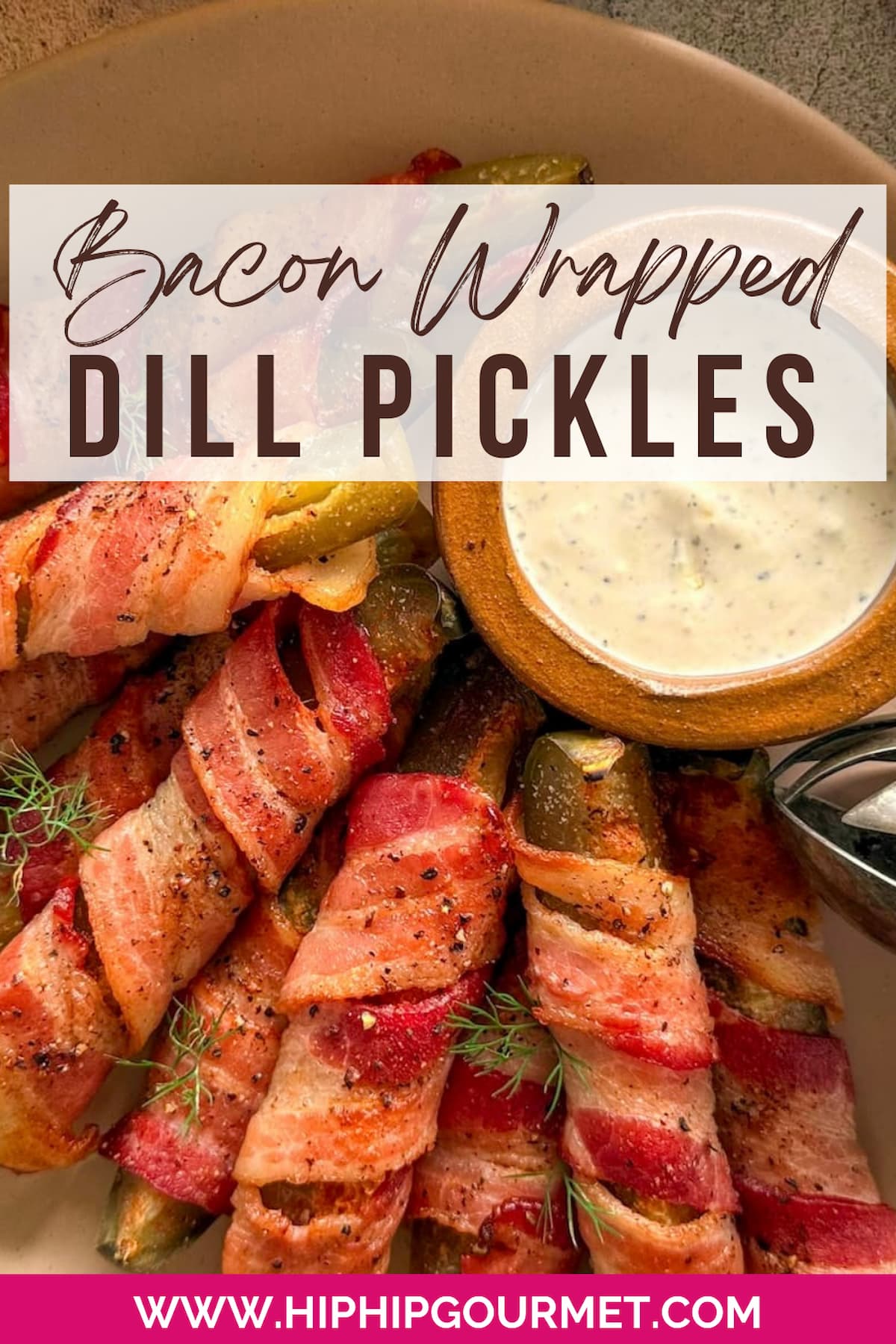 plate of bacon wrapped pickles with fresh dill on top. small ramekin with ranch dipping sauce on the plate.
