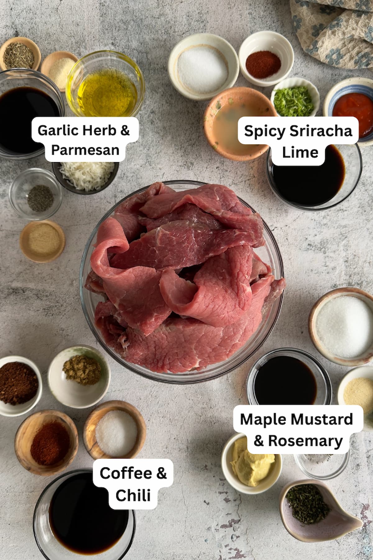 bowl of raw sliced meat in the middle, surrounded by different ramekins of different ingredients to make four different kinds of beef jerky.