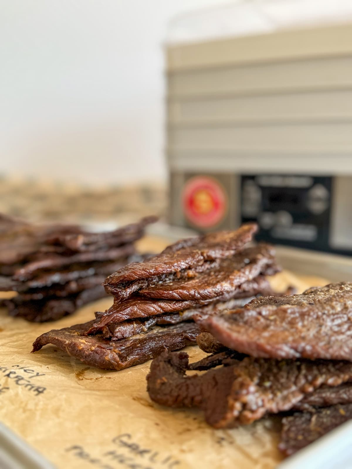 piles of beef jerky in front of a dehydrator.