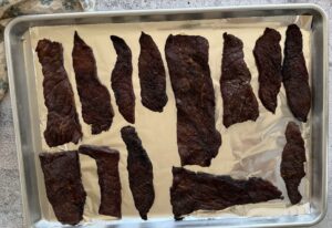 pieces of beef jerky on a foil lined baking sheet.